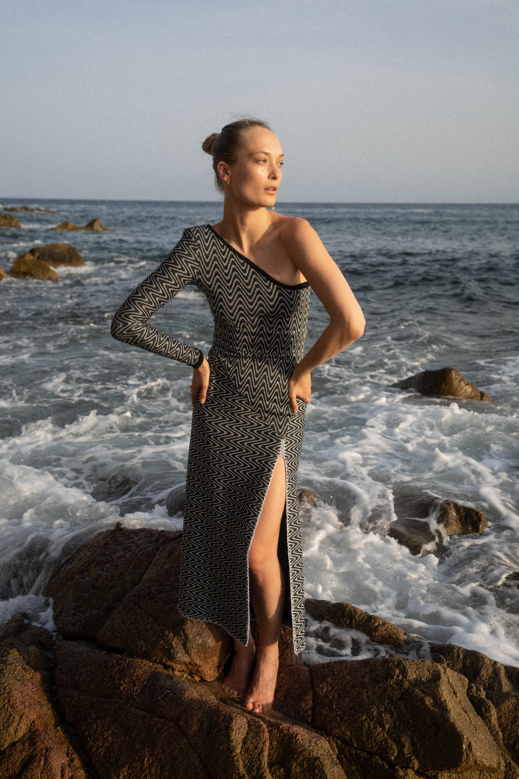 Michonet – Robe Asimetrico Silver, mannequin en robe longue asymétrique noire et blanche, sur des rochers