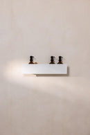 Duschablage SHEA in Weiß mit drei Flaschen für Duschzubehör an der Wand montiert.