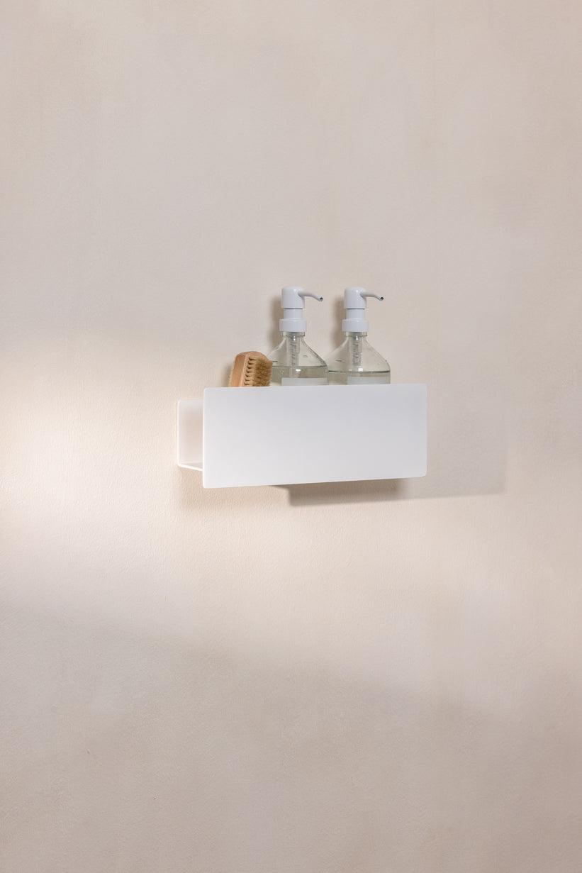 Duschablage SHEA mit dos Seifenspendern und einer Bürste auf einer Wand im Bad.