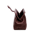 Burgundy in a shade of dark cherry leather handbag with an open rope closure on a white background