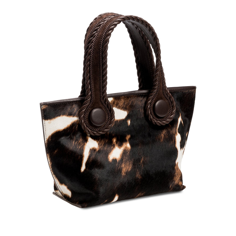 Dark brown and cream cow print pattern small tote bag with dark brown rope handles on a white background.