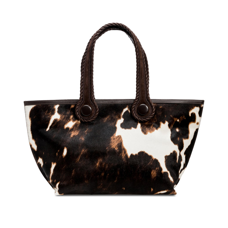 Dark brown and cream cow print pattern tote bag with dark brown rope handles on a white background.