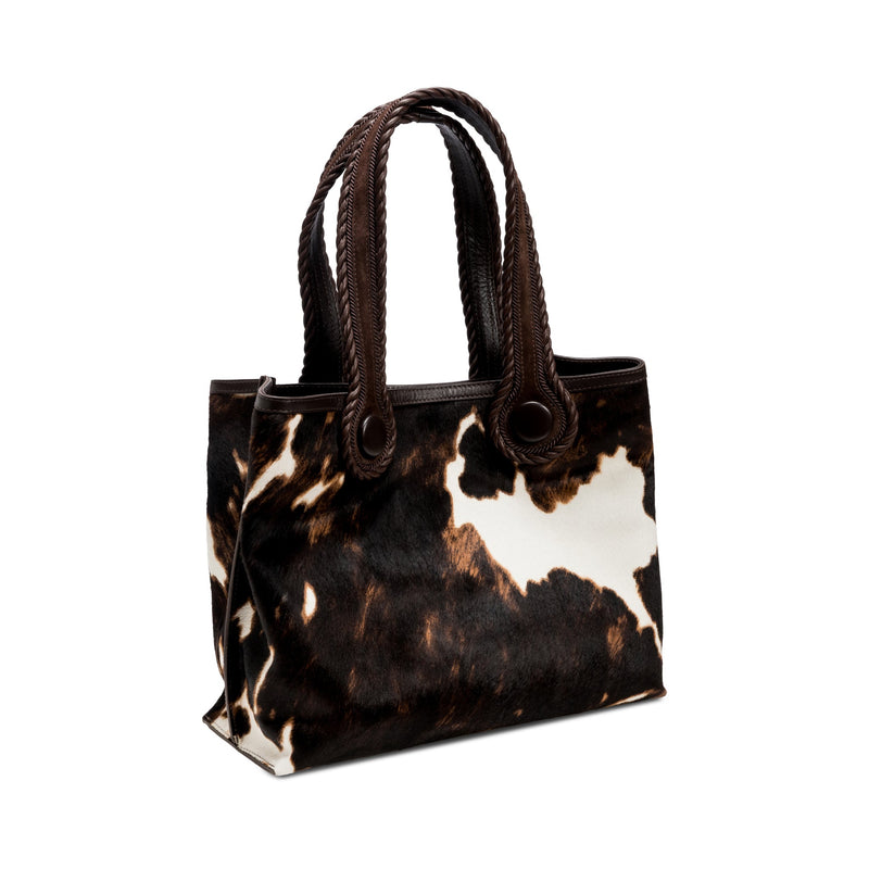Dark brown and cream cow print pattern tote bag with dark brown rope handles on a white background. When the inner straps are joined, the bag takes on a more rounded shape.
