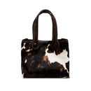 Dark brown and cream cow print pattern tote bag with dark brown rope handles on a white background. When the inner straps are joined, the bag takes on a more rounded shape.