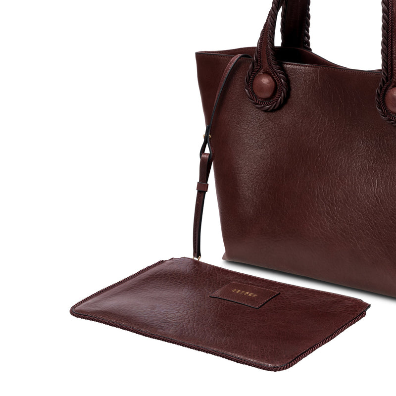 Burgundy leather in a shade of dark cherry tote bag with rope handles on a white background. It has a  removable inner bag in same color tone.
