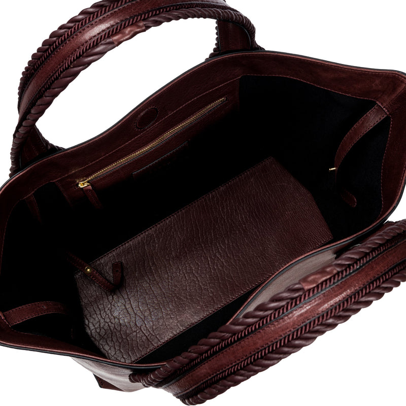 Close-up of a burgundy leather in a shade of dark cherry bag with a same tone interior. It has an inner pocket with zip and keys strap.
