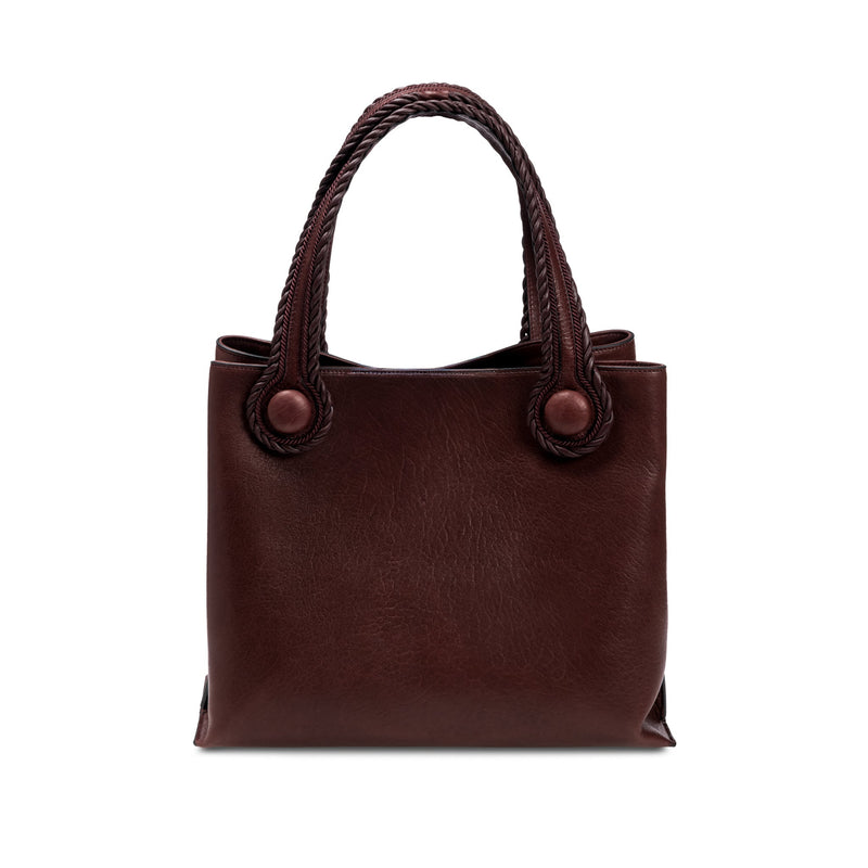 Burgundy leather in a shade of dark cherry tote bag with rope handles on a white background. When the inner straps are joined, the bag takes on a more rounded shape.