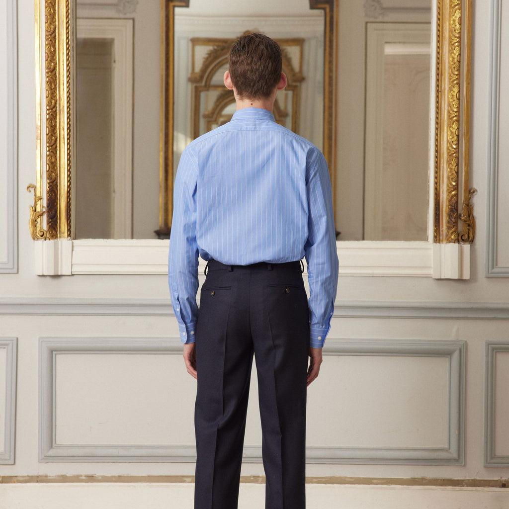 Hast – Camicia In Popeline Blu A Righe Sottili Bianche, uomo di spalle che indossa una camicia blu e pantaloni scuri