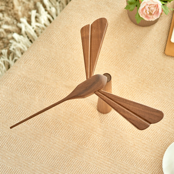 Gingko Design – Luz Libélula - Arce, un ventilador de mesa de madera marrón colocado sobre un mantel beige