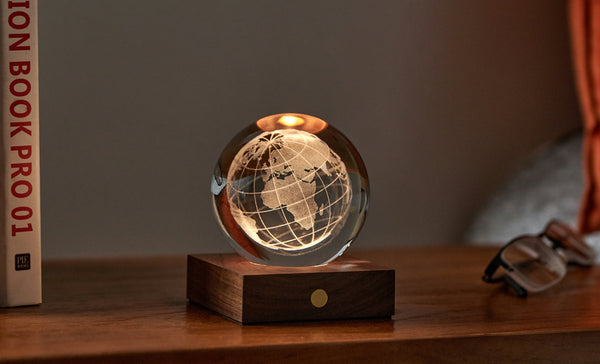 Gingko Design – Luz Amber Crystal - Globo, lámpara de noche en forma de globo terráqueo, colocada sobre una mesa de madera
