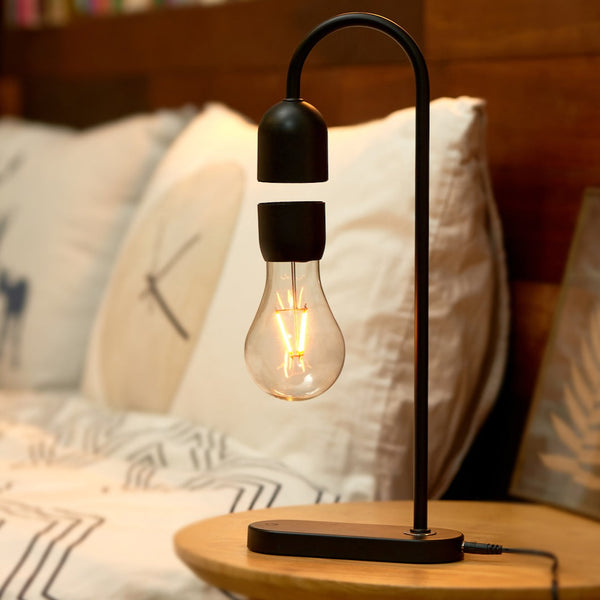 Gingko Design – Lámpara Evaro Lightbulb - Negro, lámpara de noche negra con bombilla levitante, colocada sobre una mesa de madera