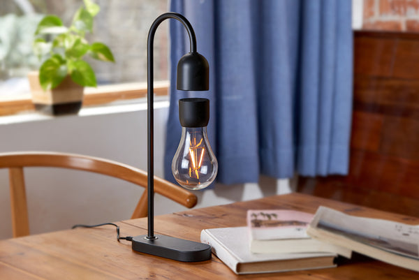 Gingko Design – Lámpara Evaro Lightbulb - Negro, lámpara de mesa negra con bombilla levitante sobre una mesa de madera