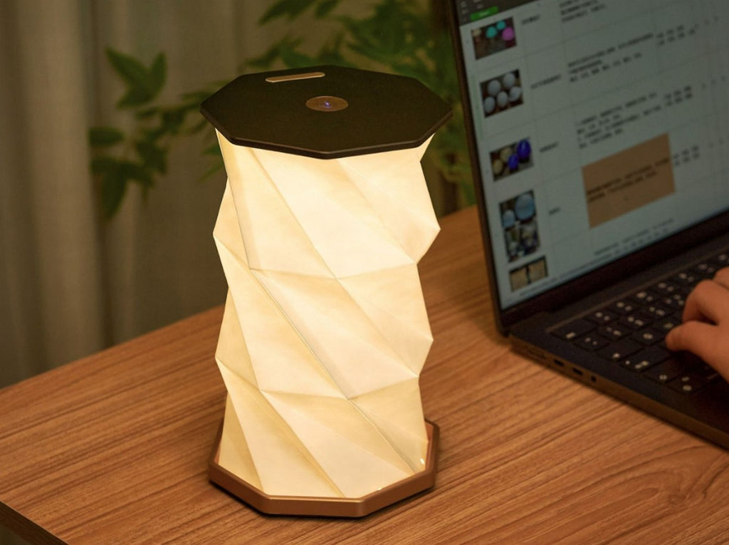 Gingko Design – Luz Twist Hexagon - Nogal Macizo, lámpara de mesa geométrica encendida, colocada sobre un escritorio de madera