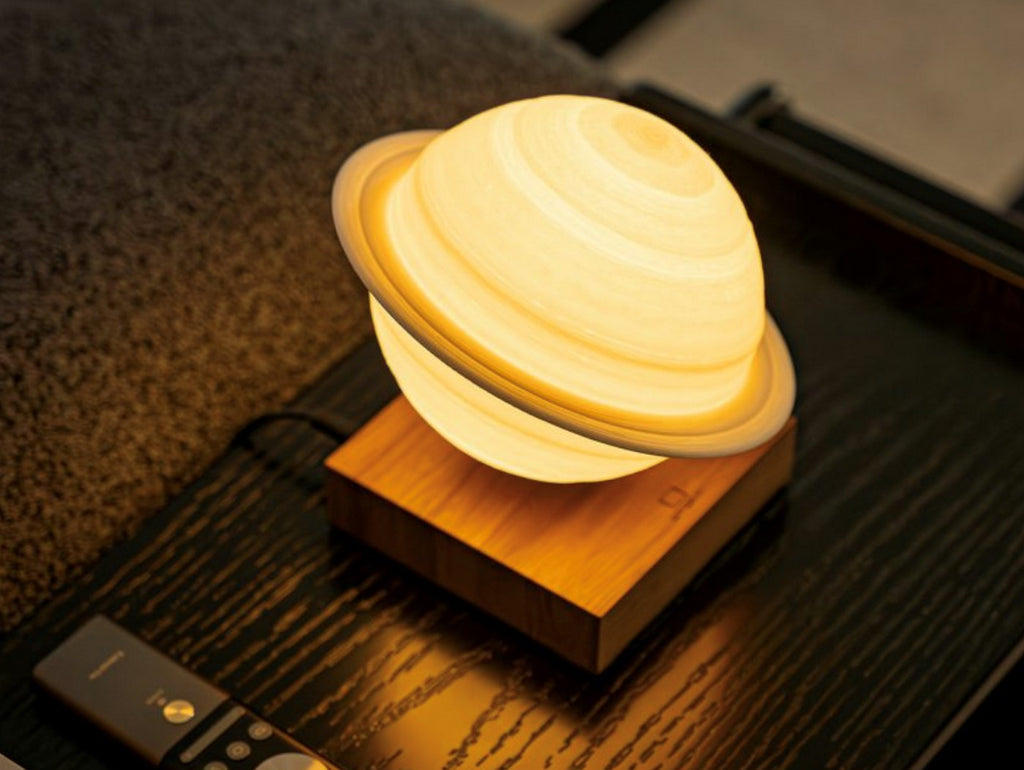 Gingko Design – Smart Saturn Lampe - Walnuss, Nachttischlampe in Form des Planeten Saturn, auf einem Nachttisch platziert