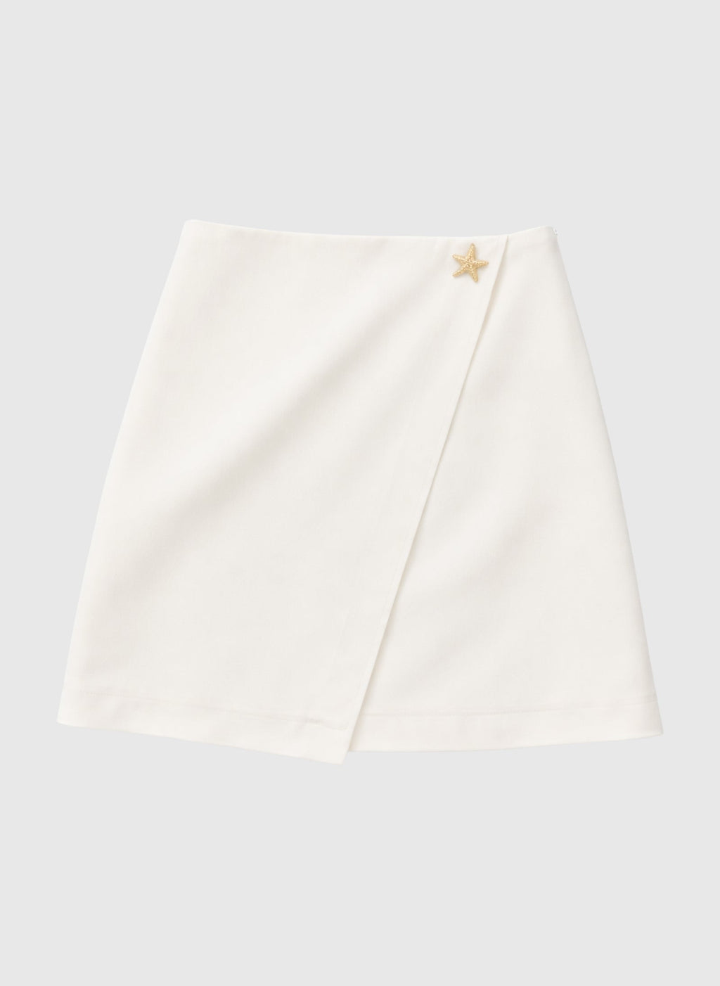 An'ge – Jupe Courte Giovani Ecru, mini-jupe portefeuille blanche avec un détail étoile dorée sur le côté