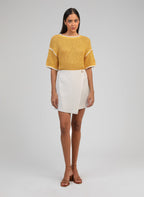An'ge – Jupe Courte Giovani Ecru, mannequin portant un pull jaune en maille et une jupe blanche