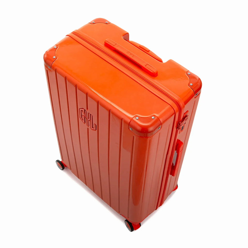 Vista en ángulo de la maleta rígida GYL Intemporelle naranja con esquinas reforzadas y carcasa nervada brillante. #couleur_orange foncé