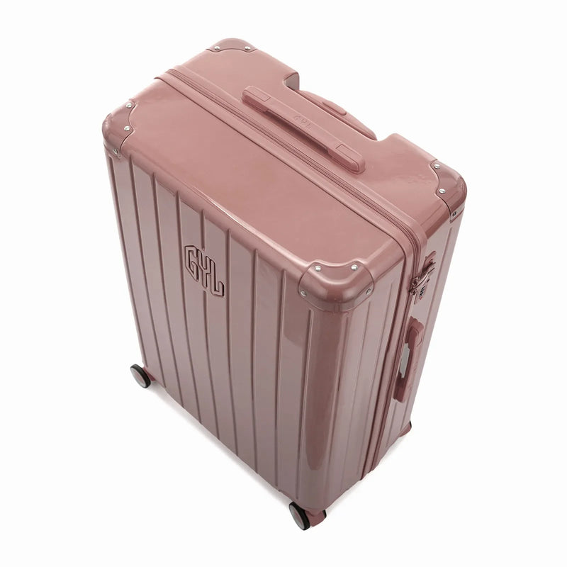 Angled view of the GYL Intemporelle rose gold hard suitcase with reinforced corners and shiny ribbed shell. #color_rose gold