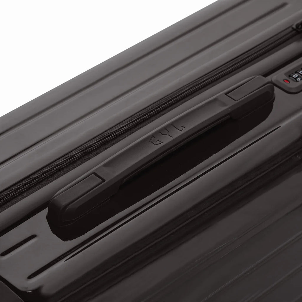 Rigid top handle of the black GYL Intemporelle suitcase with embossed logo on the top. #black_color