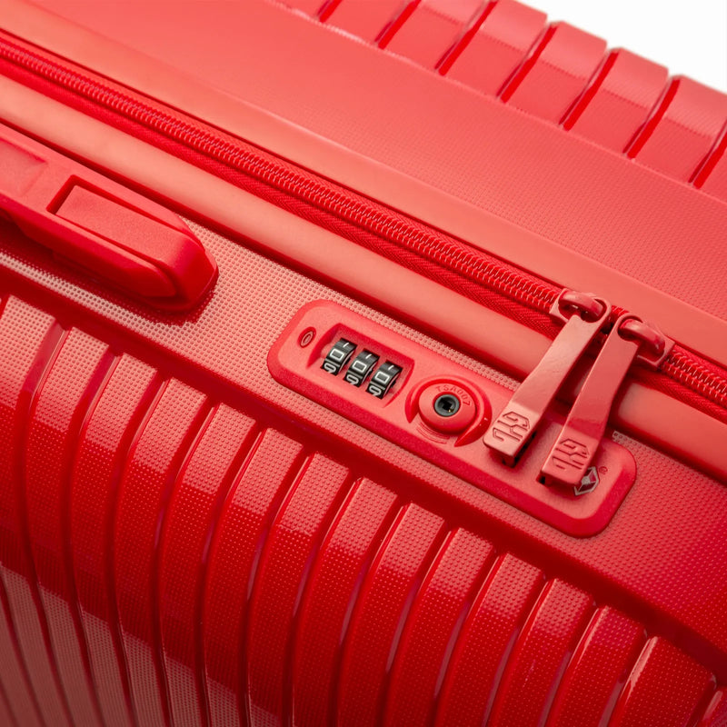 Détail de la serrure TSA intégrée et des curseurs sur la valise Signature rouge. #couleur_rouge