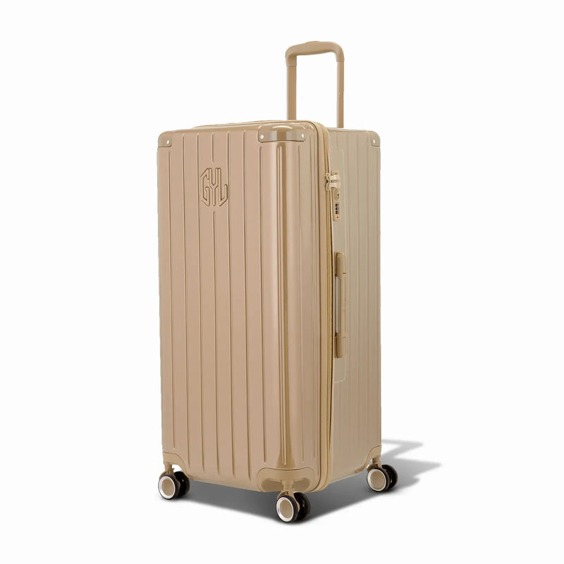 Valise trunk GYL taille XL en polycarbonate champagne vue de trois quarts, avec trolley déployé et roues 360°. #couleur_champagne