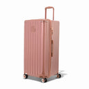 Valise trunk GYL taille XL en polycarbonate rose gold vue de trois quarts, avec trolley déployé et roues 360°. #couleur_rose gold