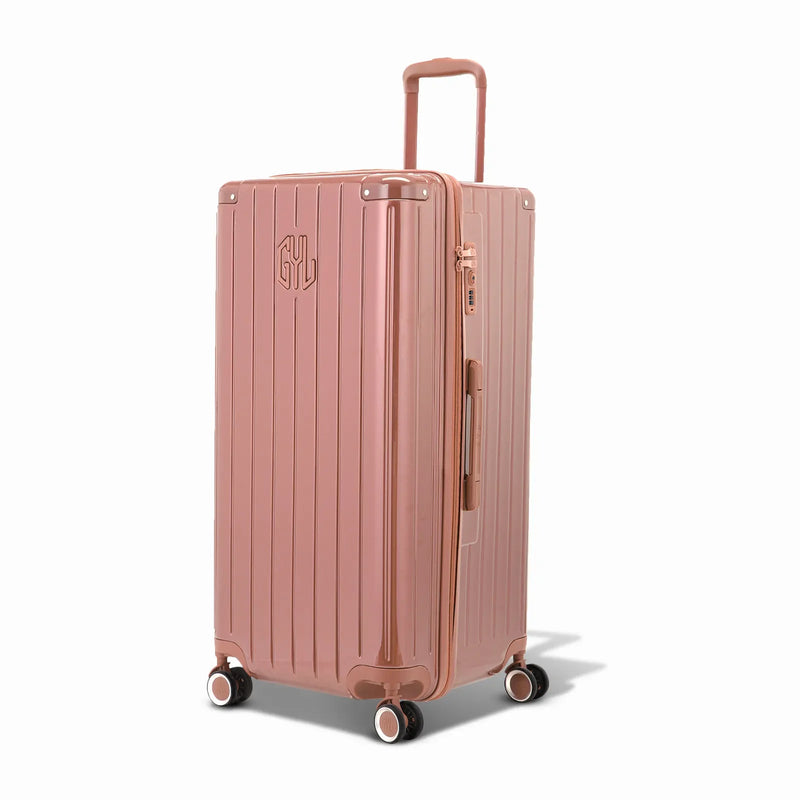 Maleta baúl GYL tamaño XL en policarbonato color oro rosa vista tres cuartos, con carro desplegado y ruedas de 360°. #color_oro rosa