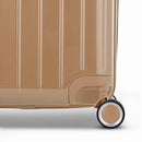 Detalle de la rueda y logo GYL en el fondo de la maleta baúl champagne en policarbonato brillo. #color_champán