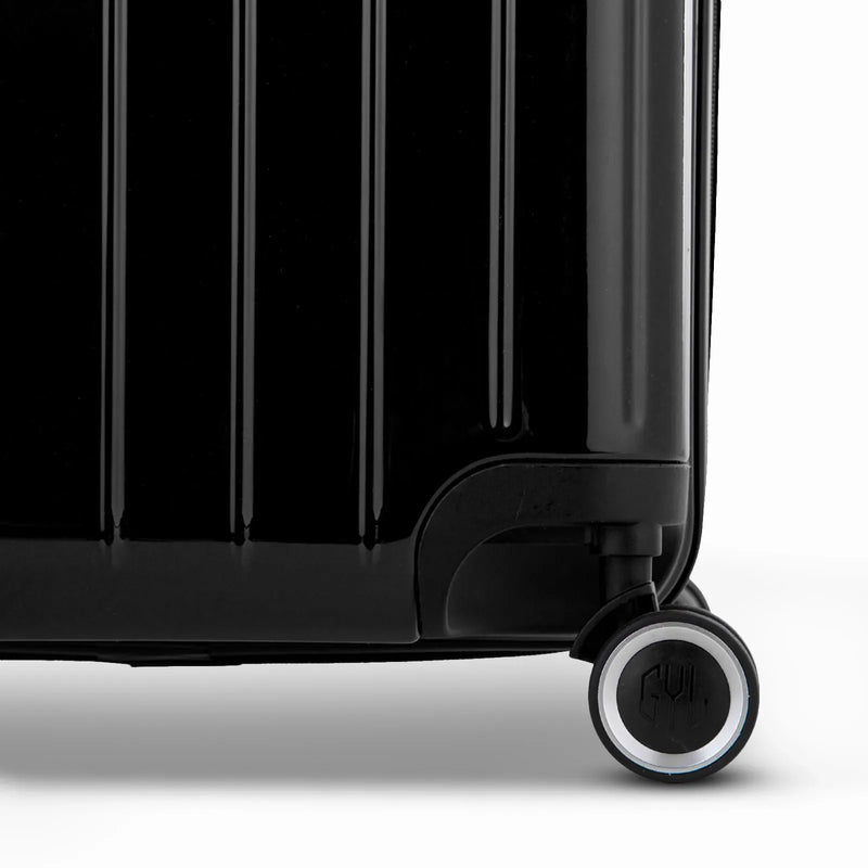 Detalle de la rueda y el logo GYL en el fondo de la maleta baúl de policarbonato negro brillo. #color_negro