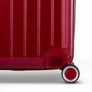 Detalle de la rueda y el logo GYL en el fondo de la maleta baúl rojo oscuro en policarbonato brillo. #color_rojo_oscuro