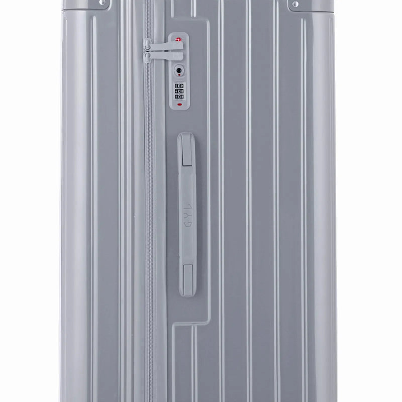 Détail de la serrure TSA et de la poignée latérale sur la valise trunk argent. #couleur_argent