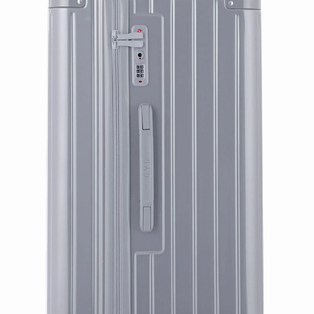 Détail de la serrure TSA et de la poignée latérale sur la valise trunk argent. #couleur_argent
