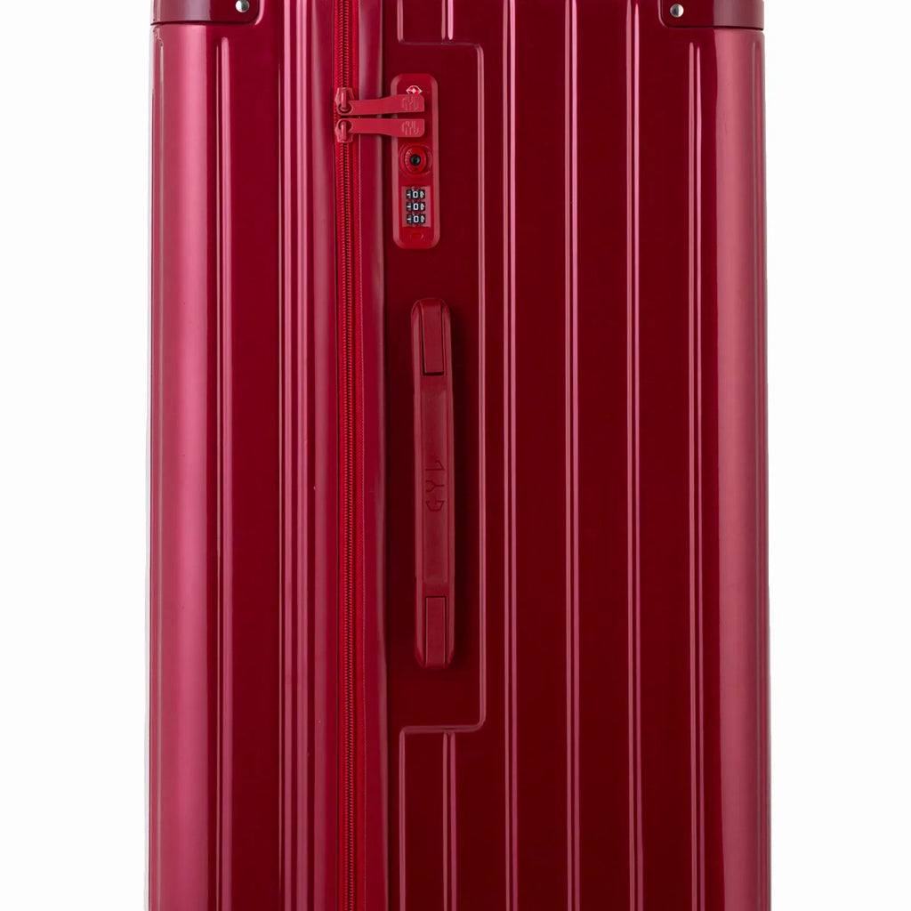 Détail de la serrure TSA et de la poignée latérale sur la valise trunk rouge foncé. #couleur_rouge foncé