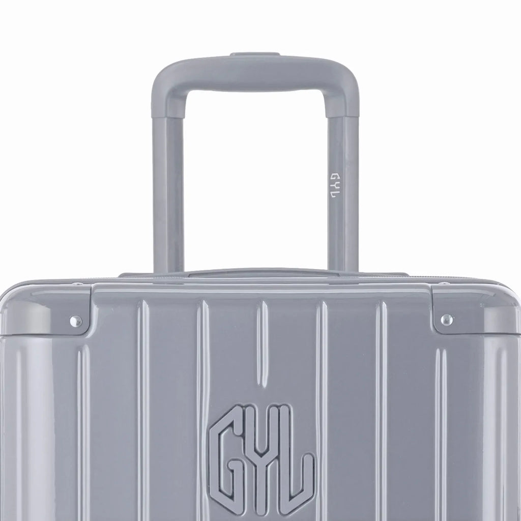 Zoom sur la poignée trolley et le logo GYL de la valise trunk argent. #couleur_argent