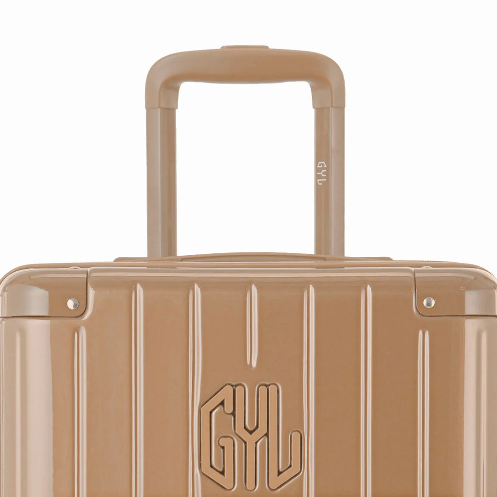 Zoom sur la poignée trolley et le logo GYL de la valise trunk champagne. #couleur_champagne