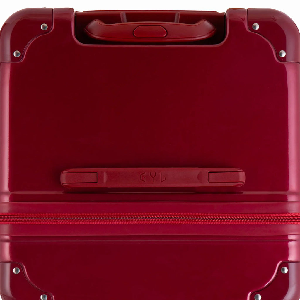 Vue du dessus de la valise trunk GYL rouge foncée en polycarbonate, avec poignée centrale et coins renforcés. #couleur_rouge foncé