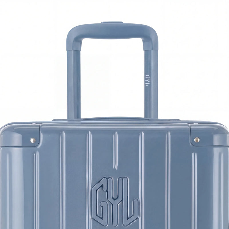 Zoom sur la poignée trolley et le logo GYL de la valise trunk bleu gris. #couleur_bleu grisé