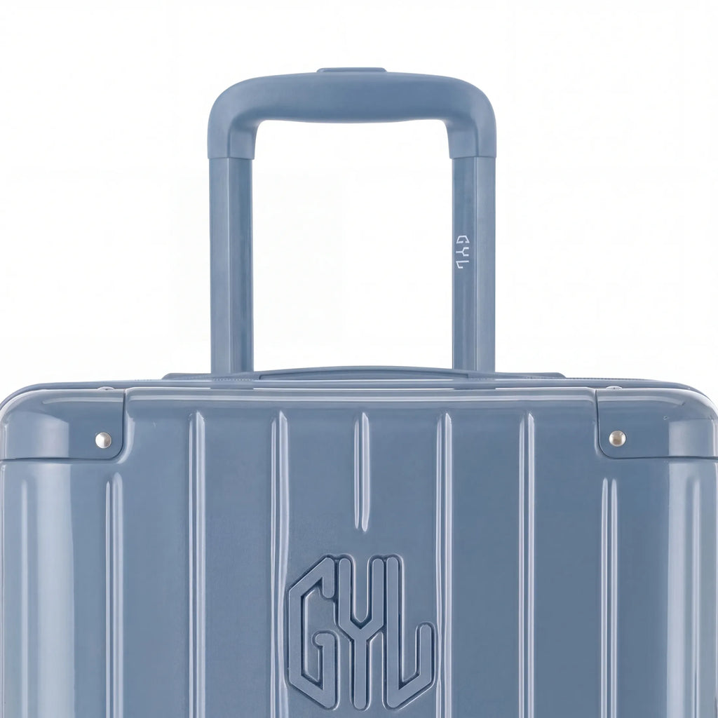 Zoom sur la poignée trolley et le logo GYL de la valise trunk bleu gris. #couleur_bleu grisé