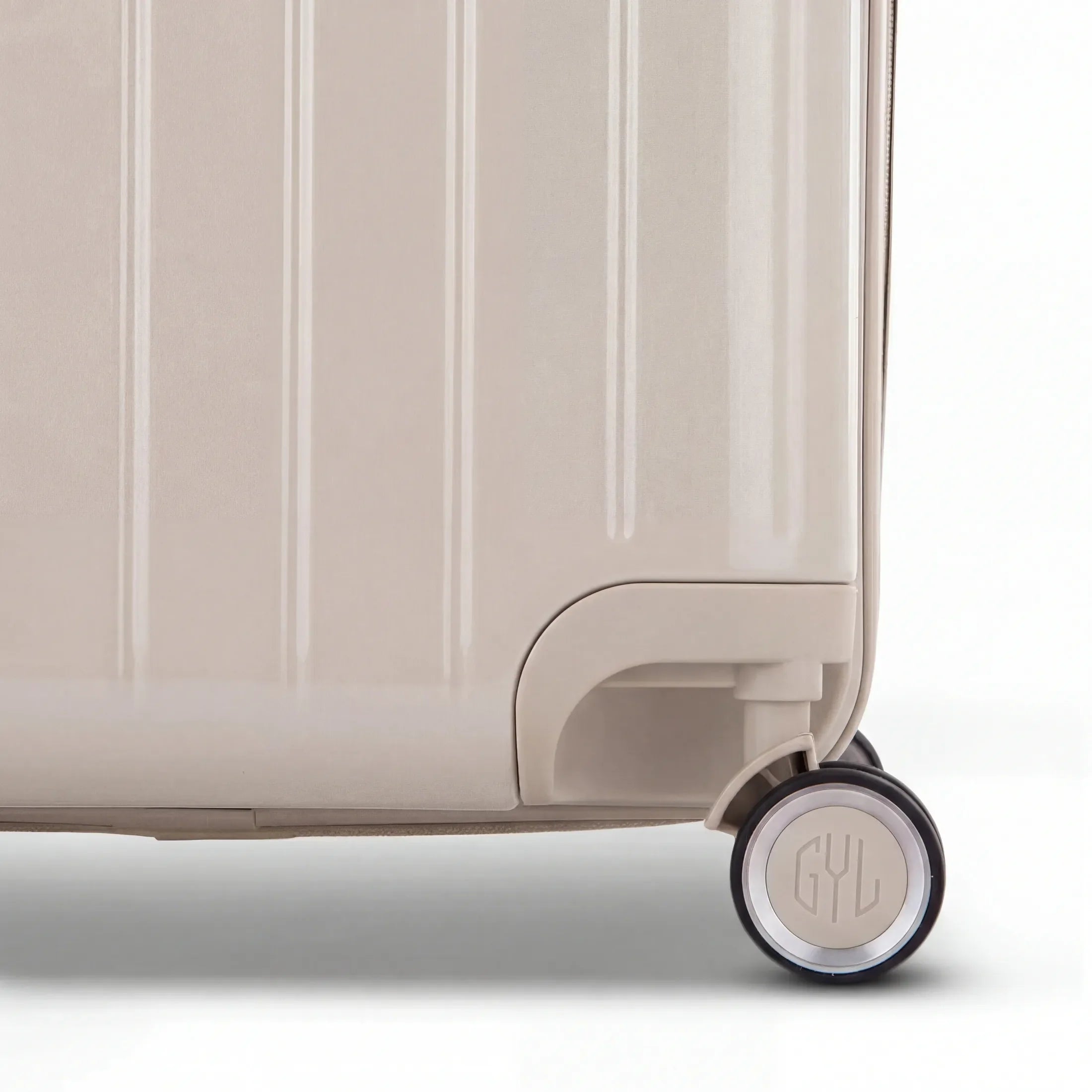 Détail de la roue et du logo GYL sur le bas de la valise trunk nude en polycarbonate brillant. #couleur_nude