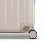 Détail de la roue et du logo GYL sur le bas de la valise trunk nude en polycarbonate brillant. #couleur_nude