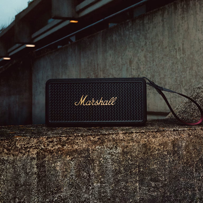 Marshall – Middleton II - Altavoz Portátil - Black & Brass, altavoz negro colocado sobre un muro de hormigón, vista frontal