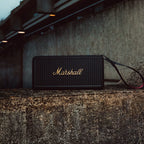 Marshall – Middleton II - Altavoz Portátil - Black & Brass, altavoz negro colocado sobre un muro de hormigón, vista frontal
