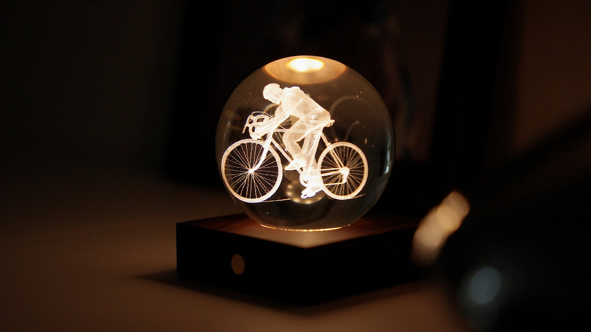Gingko Design – Amber Crystal-lampa - Cyklist, en lysande glaskula med en graverad cyklist, på en träsockel