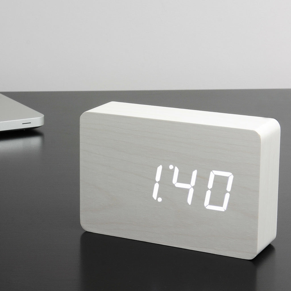 Gingko Design – Brick Click Alarm Clock - White / White LED, light wood digital alarm clock displaying the time on a dark table