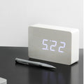 Gingko Design – Brick Click Alarm Clock - White / White LED, light wood digital alarm clock placed on a black table