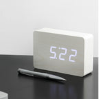 Gingko Design – Brick Click Alarm Clock - White / White LED, light wood digital alarm clock placed on a black table