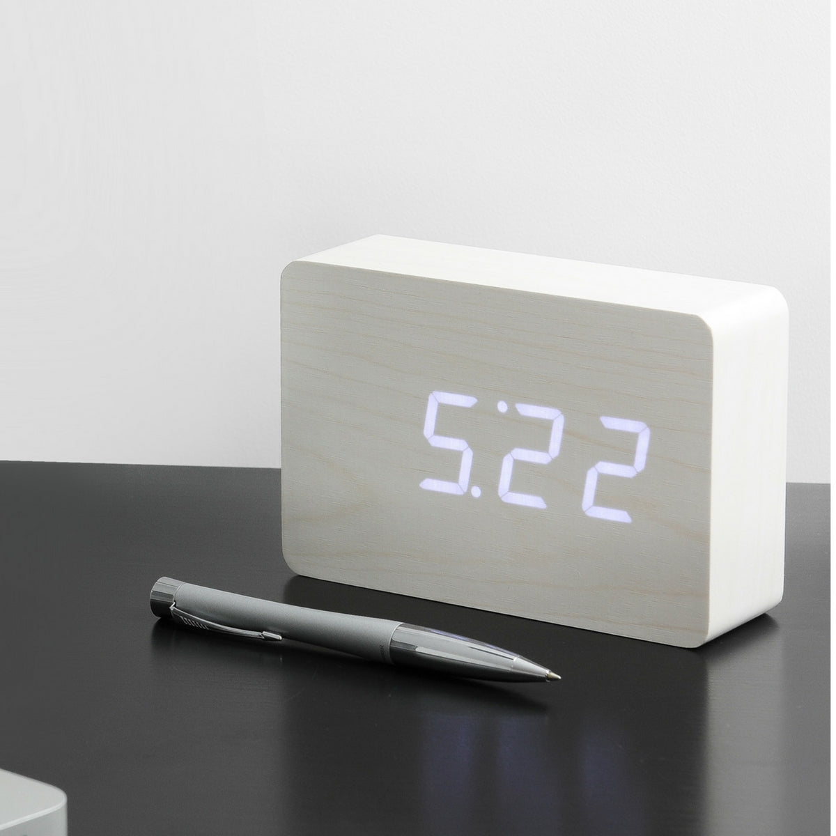 Gingko Design – Brick Click Alarm Clock - White / White LED, light wood digital alarm clock placed on a black table