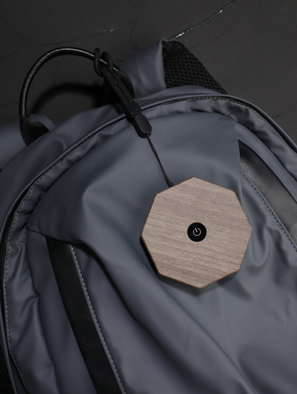 Gingko Design – Twist Hexagon Leuchte - Treibholz Walnuss - Mini, ein achteckiges Objekt aus hellem Holz mit schwarzem Knopf auf einer grauen Tasche