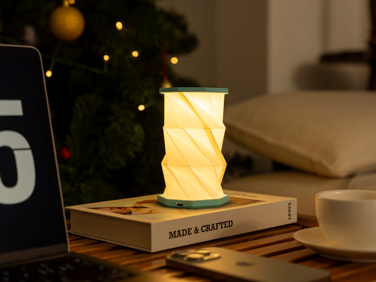 Gingko Design – Luz Twist Hexagon - Azul Laguna - Mini, lámpara de mesa luminosa sobre un libro, ambiente cálido