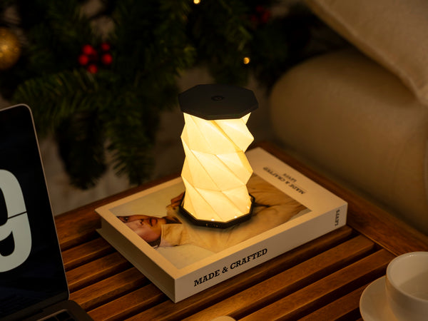 Gingko Design – Luz Twist Hexagon - Negro Pizarra - Mini, lámpara de noche encendida sobre una mesilla de noche de madera